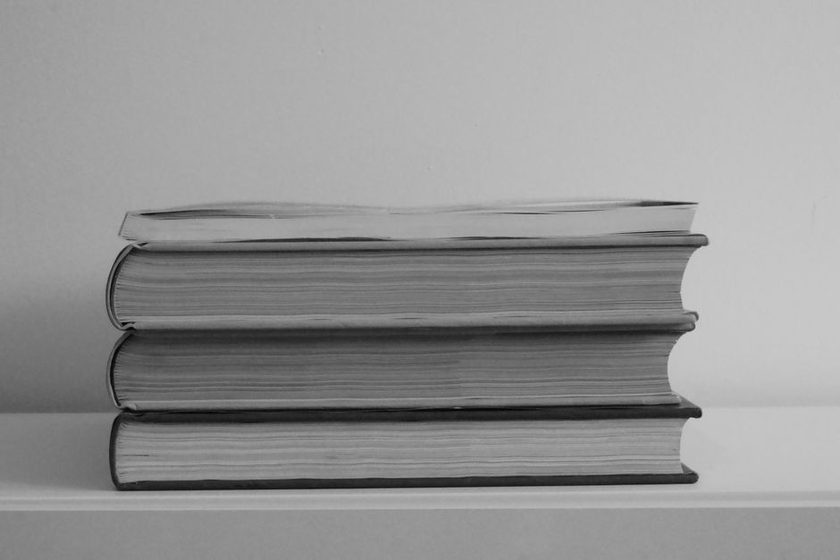 Row of worn hardcover books leaning on a shelf
